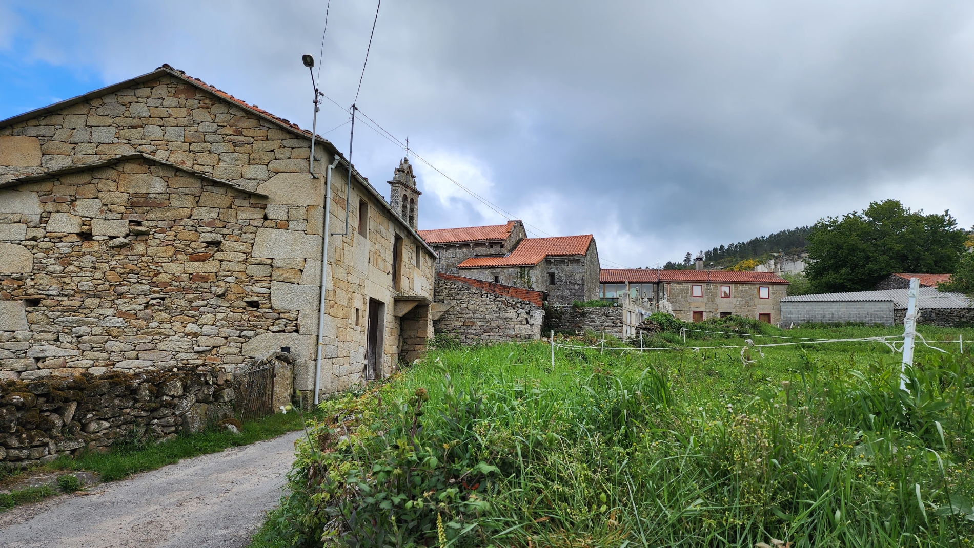 Traditional stone farmhouses and the church of San Xiao de Pedroso at A Eirexe, on the Camino de Invierno towards Lalín.